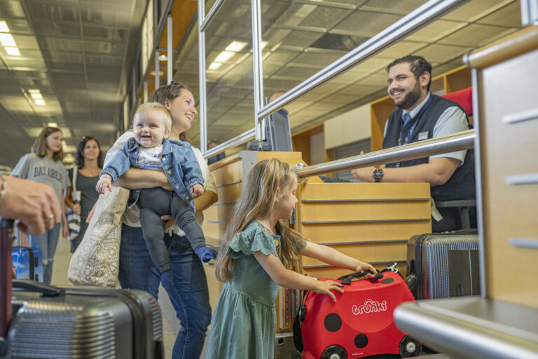 Mitarbeiter am Check In, der eine Familie eincheckt